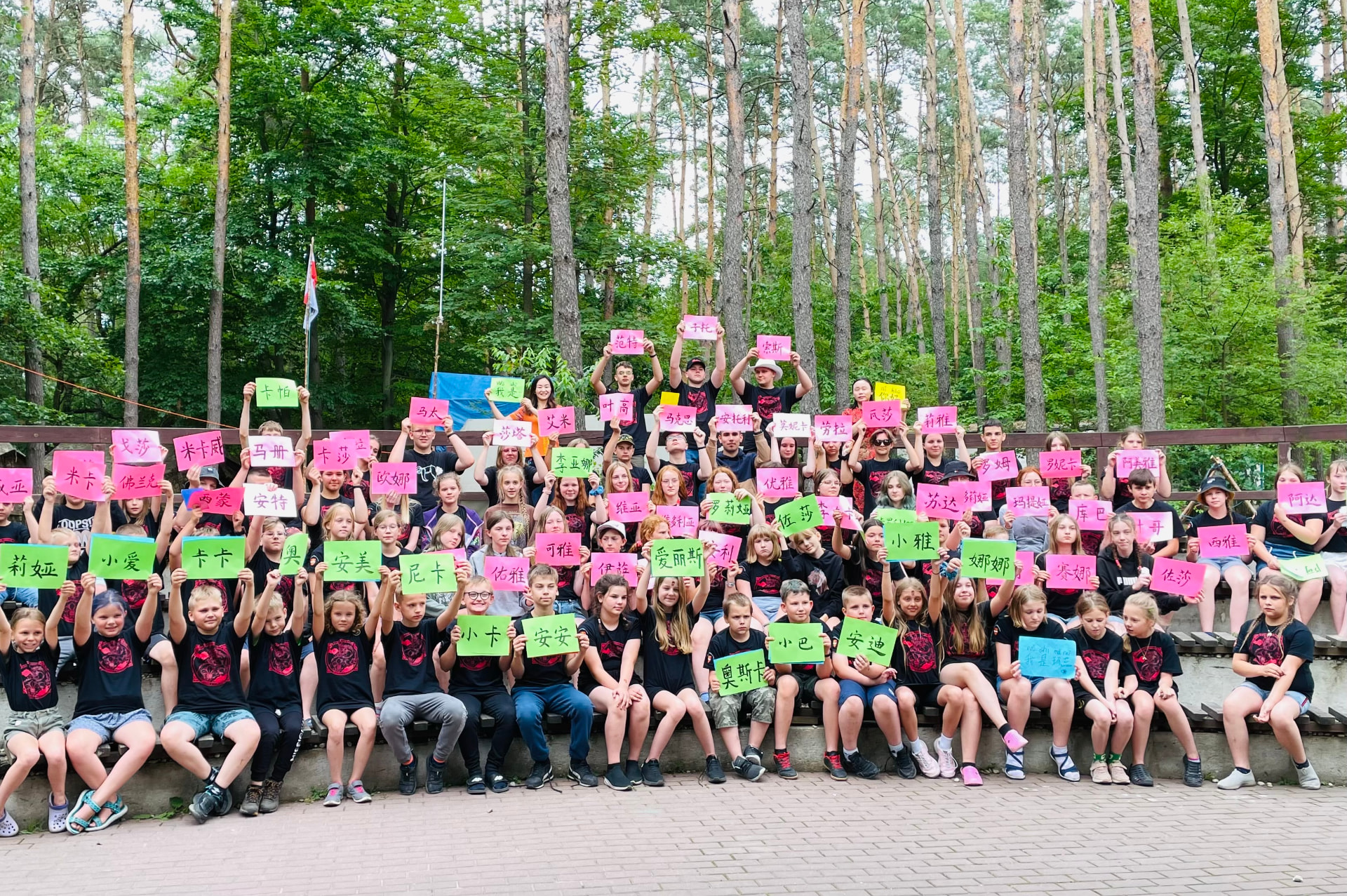 Students holding Chinese name signs during an outdoor activity