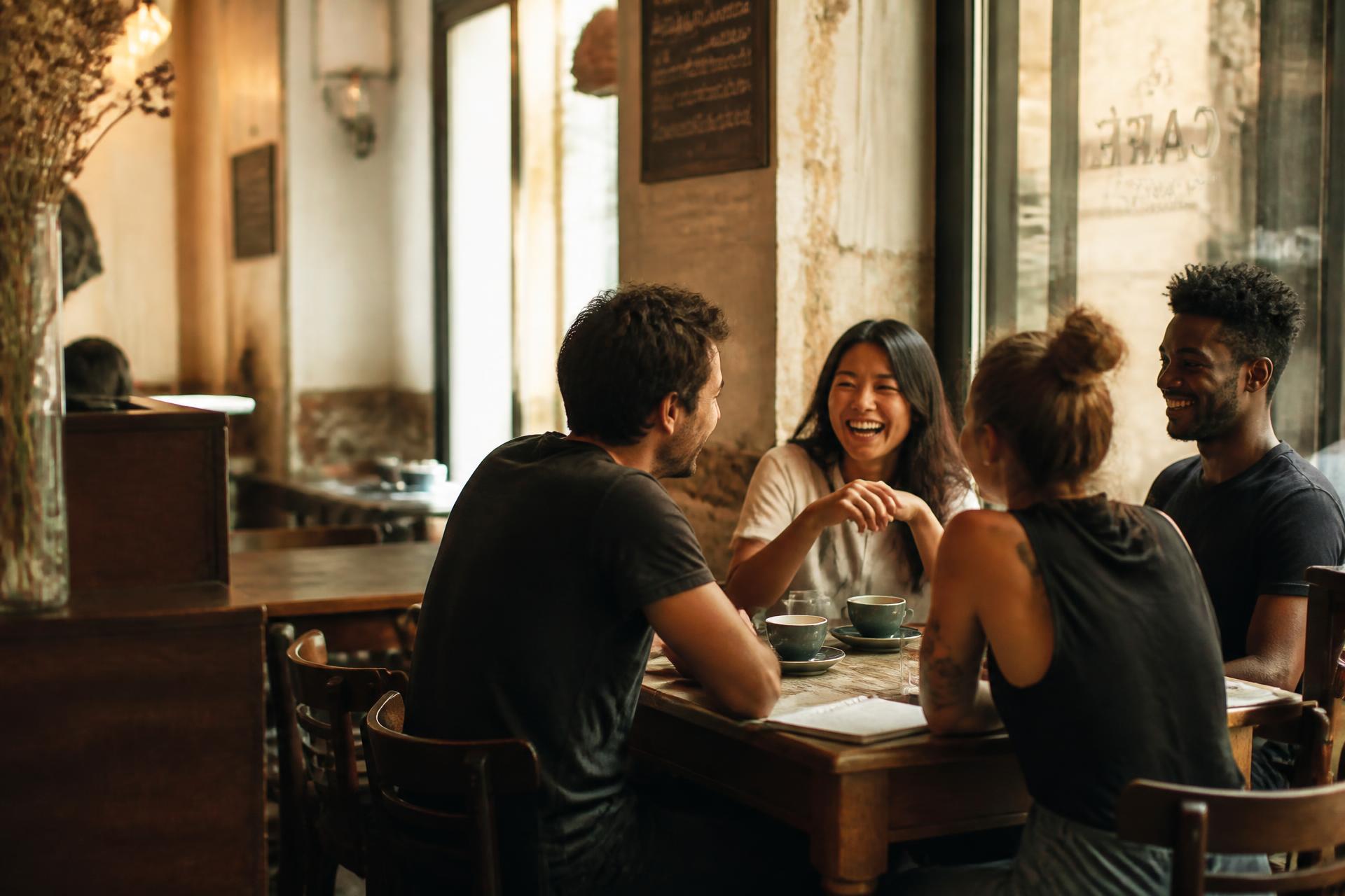 A small group of adults talking around a café table in warm afternoon light